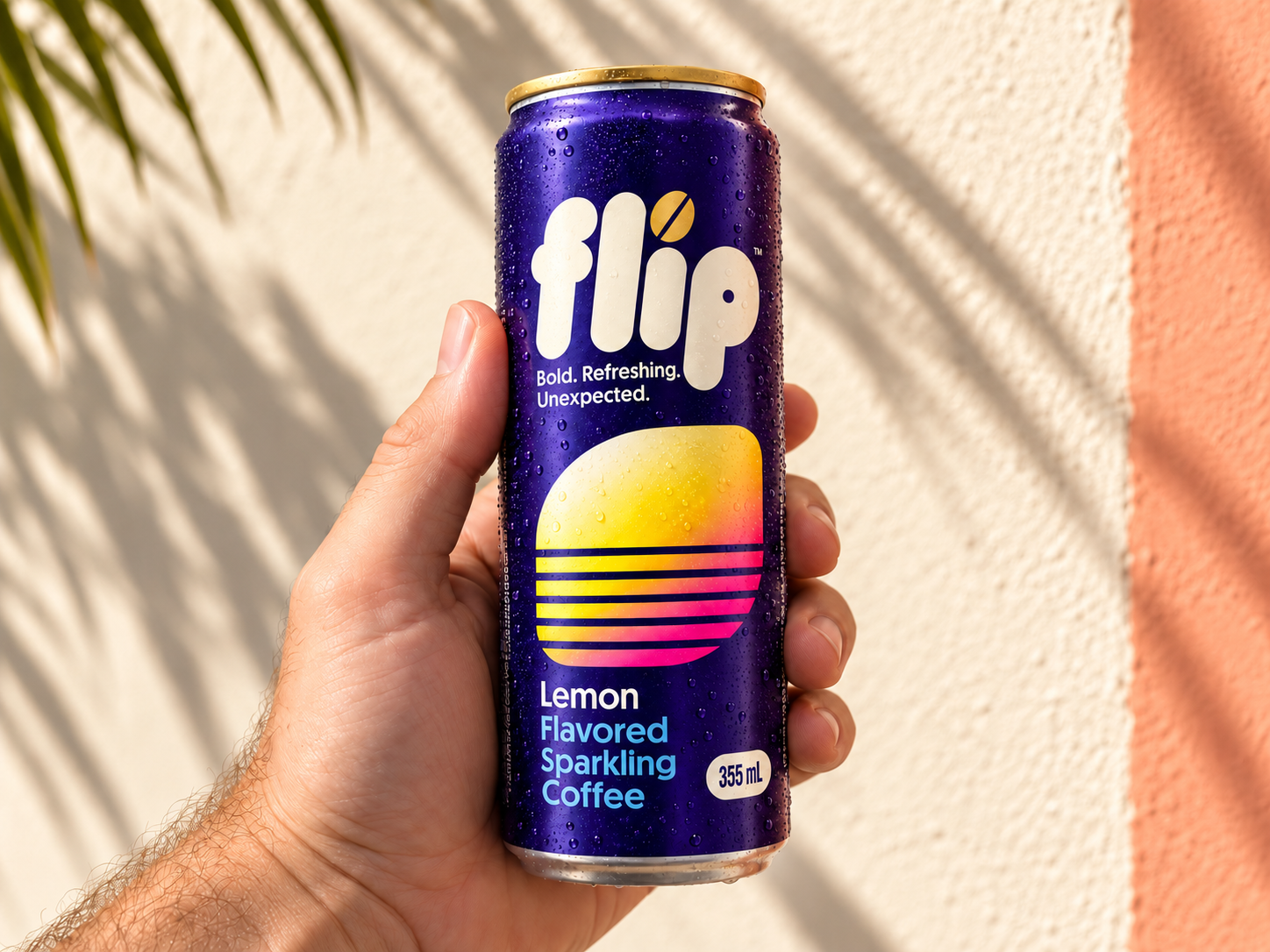 A hand holding a purple FLIP Lemon can against a cream and coral wall with palm shadows