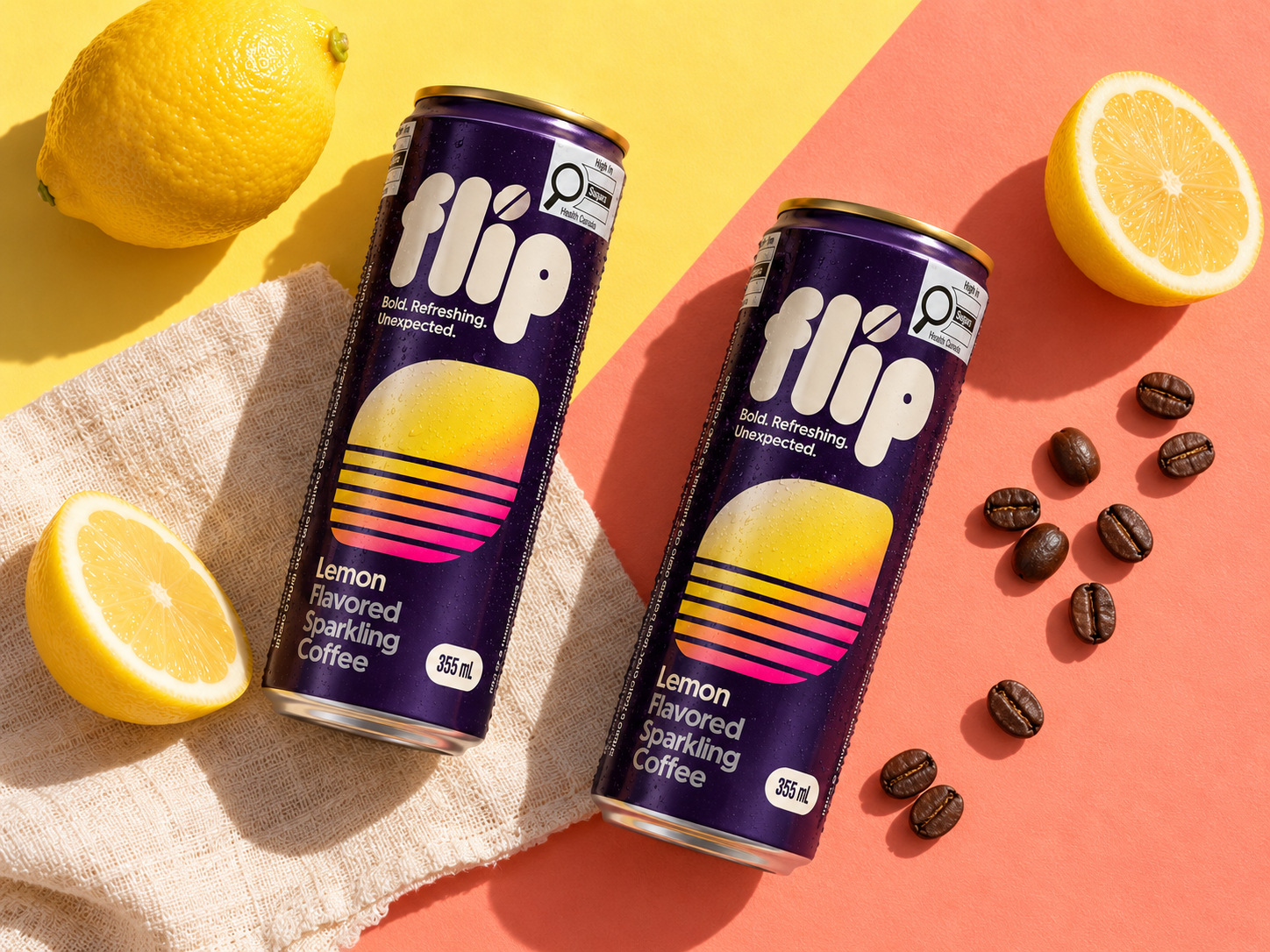 Two complete purple FLIP Lemon cans on a diagonal yellow and coral surface with lemons, linen and coffee beans